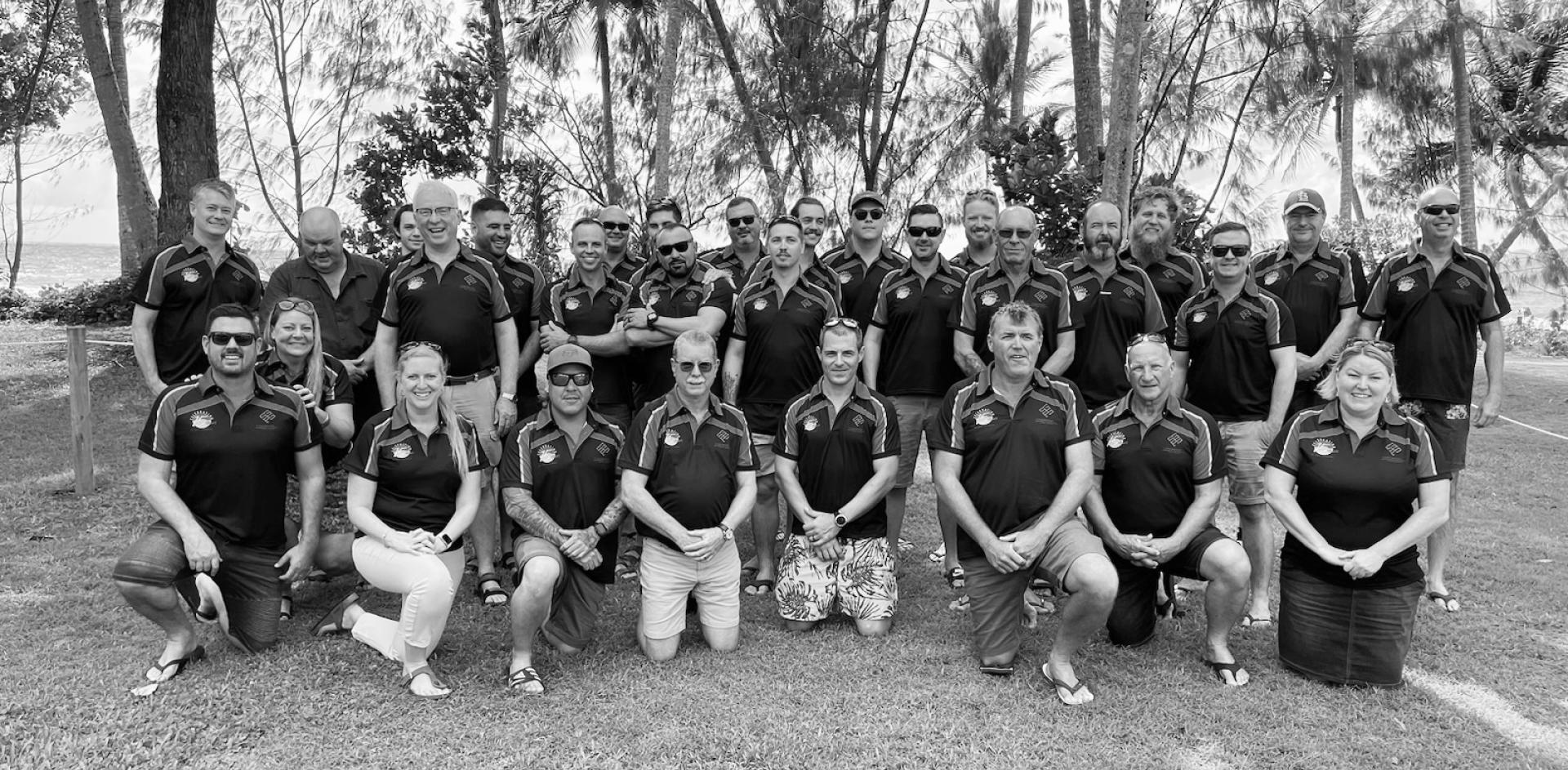 Black and white photograph of APP employees outdoors in a large grass area