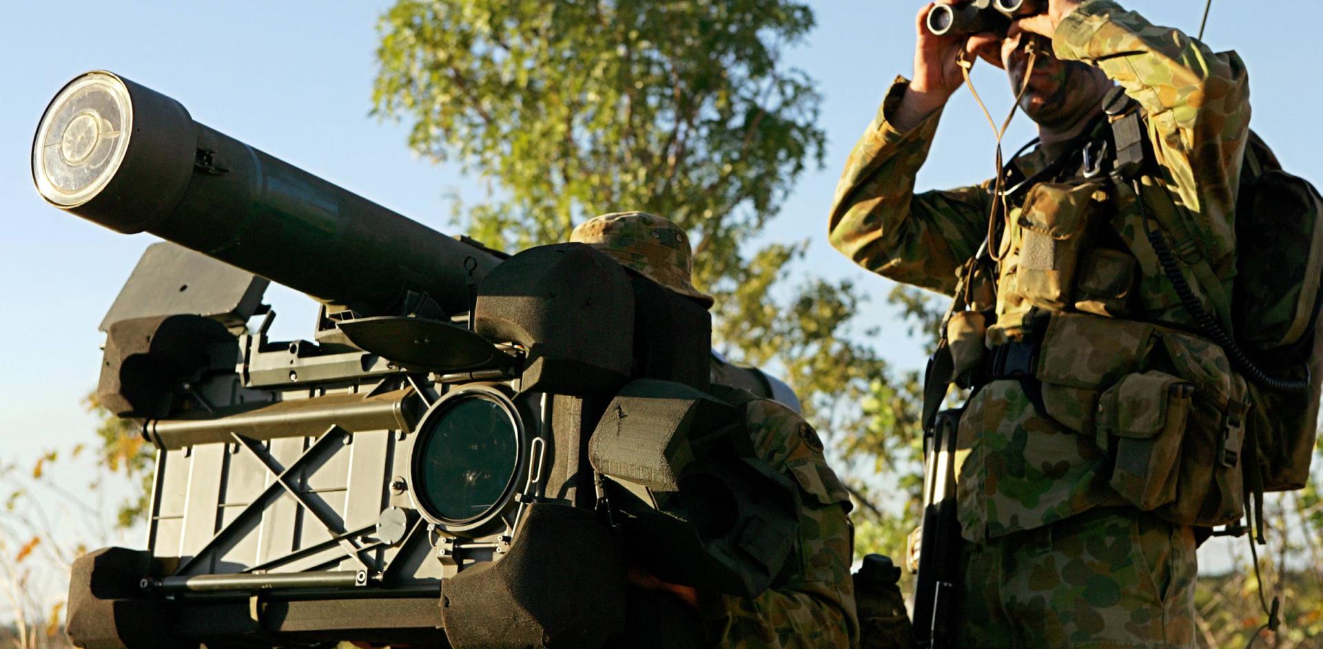Two soldiers watching something in the distance with binoculars and machinery