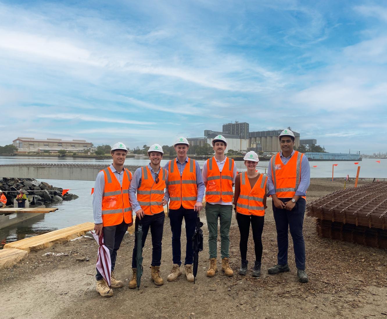 Six young people on a building site in high-visibility jackets and hard hats