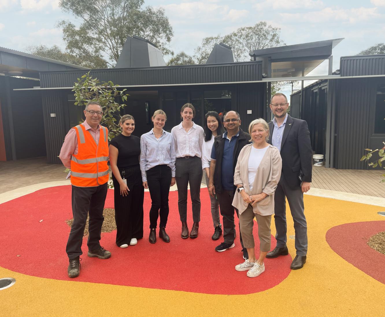 A group of eight colleagues pose for a photo on a project site