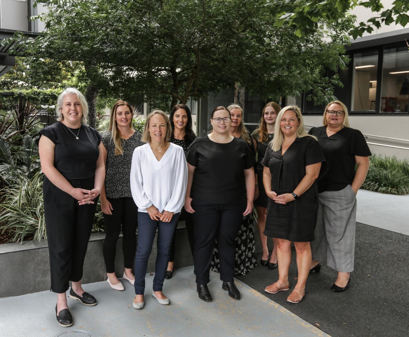 Nine woman pose for a photograph outside an office