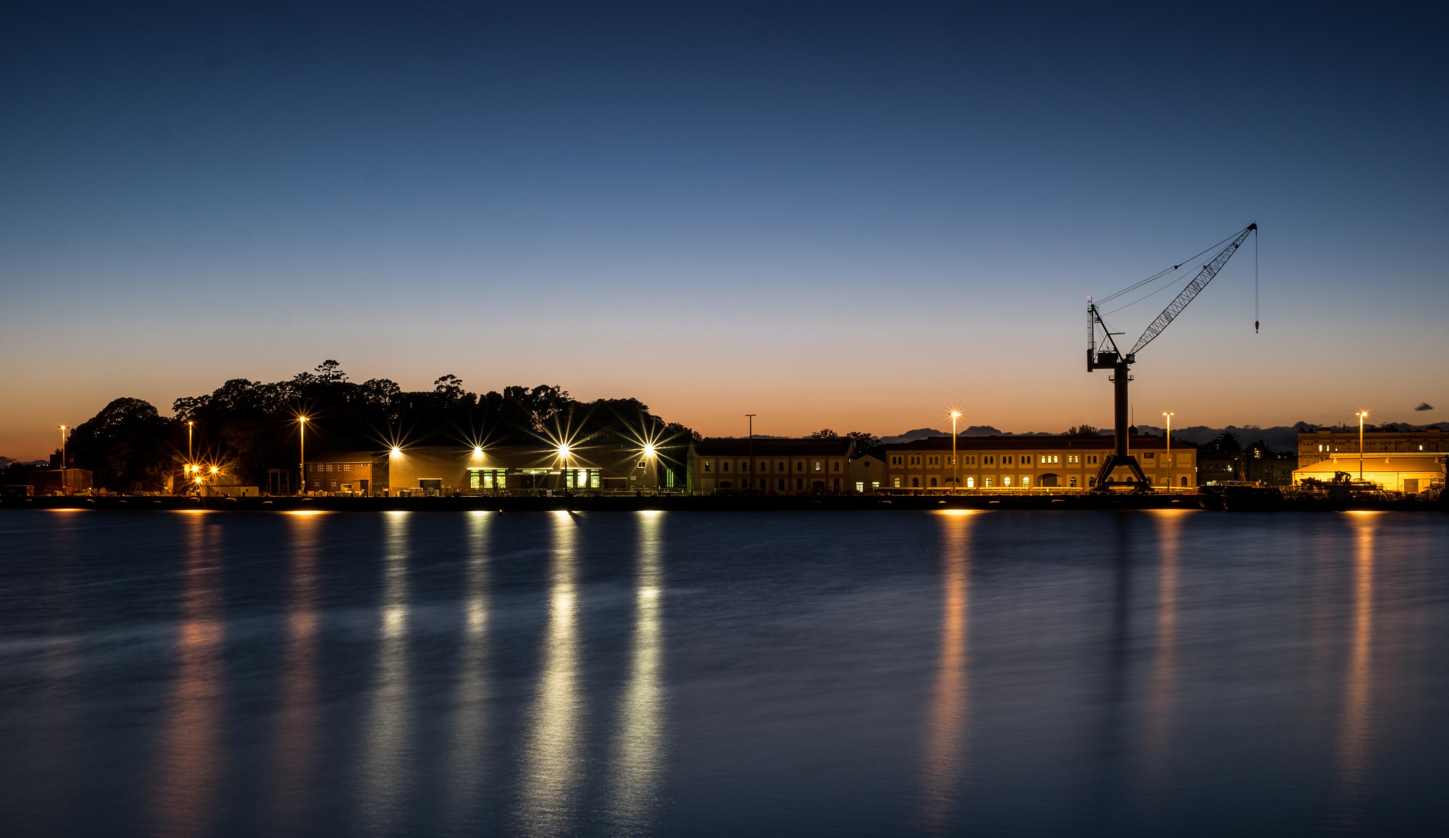 View of wharf with crane and buildings in the background at sunset