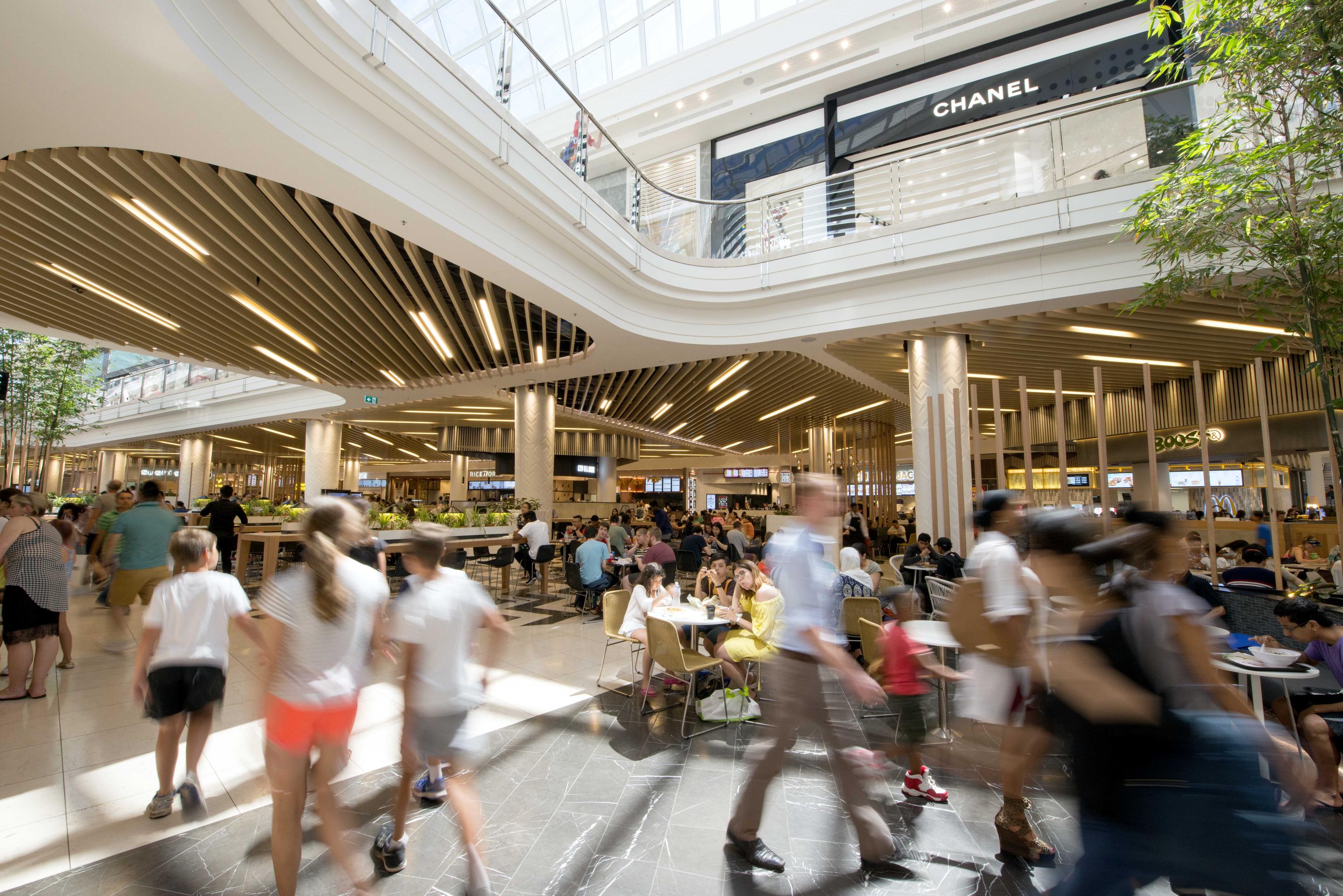 Interior view of modern shopping mall with customers walking, sitting, and talking