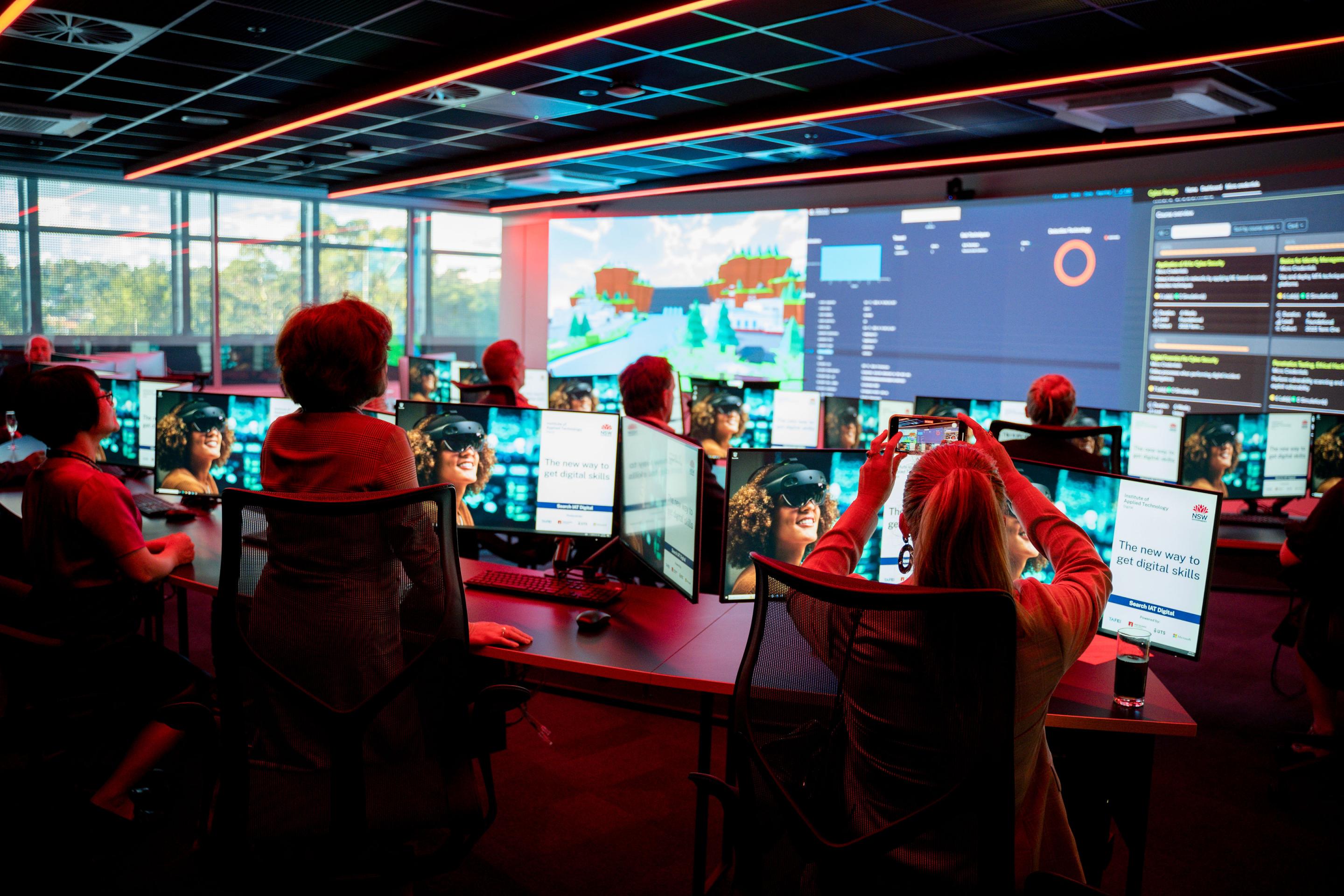 Team looking at computer screens in indoor room with red lighting