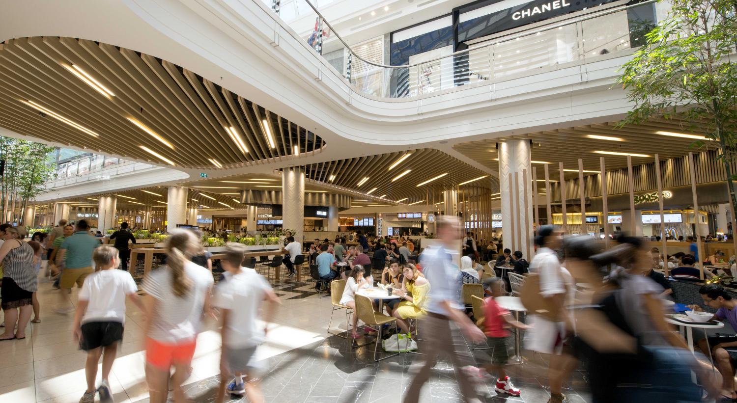 Interior view of modern shopping mall with customers walking, sitting, and talking
